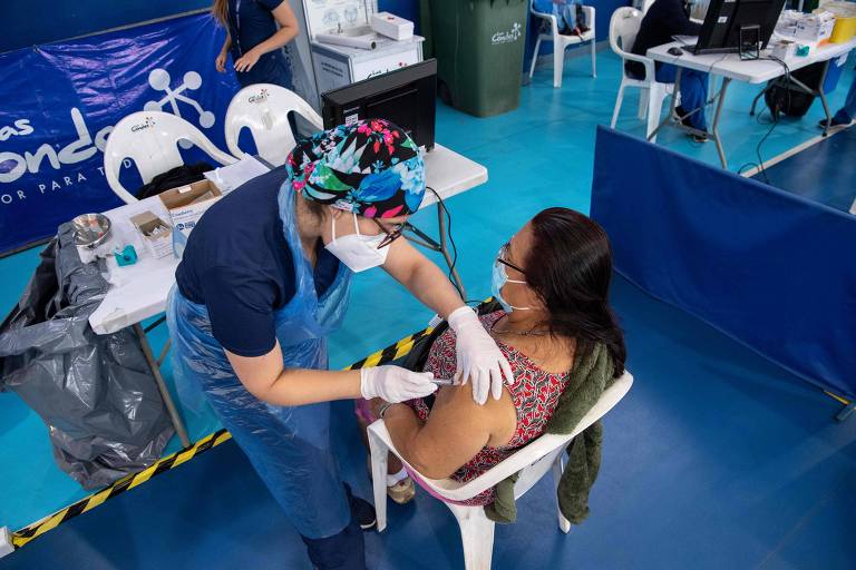 Uma profissional de saúde aplica a vacina chinesa Coronavac a um professor em um centro de vacinação em Santiago
