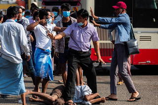 Military supporter points a sharp object as he confronts anti-coup protesters during a military support rally in Yangon