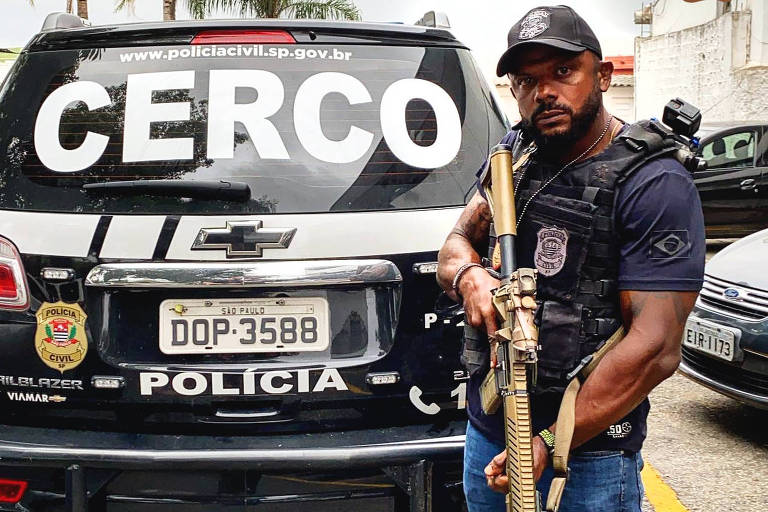 O delegado da Polícia Civil de São Paulo, Carlos Alberto da Cunha, 43, posa para foto exibindo arma