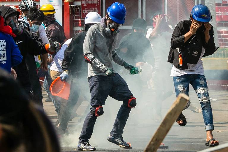 Manifestantes correm após o uso de gás lacrimogêneo pela polícia enquanto as forças de segurança reprimem manifestações contra o golpe militar, em Rangoon