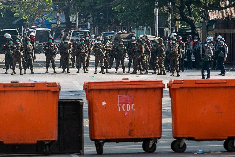 Soldados e policiais observam após os manifestantes montarem barricadas para bloqueá-los enquanto as forças de segurança reprimem as manifestações contra o golpe militar, em Rangoon