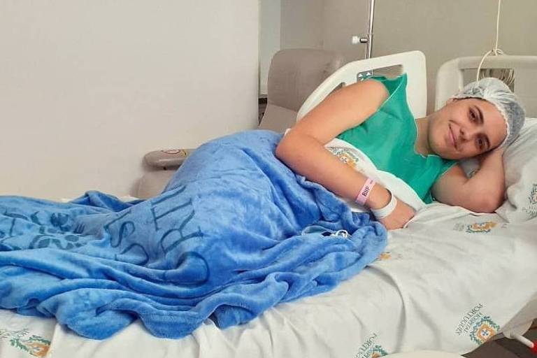 Estudante deitada em cama de hospital após doar medula óssea