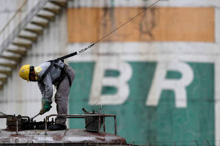 FILE PHOTO: A worker checks the fuel volumes on a train wagon near a tank of Brazil's state-run Petrobras oil company in Brasilia, Brazil