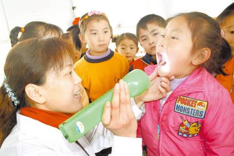 ORG XMIT: 311801_0.tif Profissional da área médica examina crianças em um jardim de infância na Província de Shandong, leste da China; iniciativa integra programa de prevenção à doença de mão, pé e boca, que se caracteriza por aftas e bolhas nos pés e nas mãos. (090403) --BOXING, April 3, 2009 (Xinhua) -- A medical worker takes mouth checks for the children at a kindergarten in Boxing county of east China's Shandong Province April 2, 2009. Different batches of medical workers were dispatched to kindergartens in rural areas of Boxing County spreading knowledge to prevent hand-foot-mouth disease (HFMD) among the children and help the kindergartens develop precautious measures against the disease. (Xinhua/Chen Bin) (zsc)