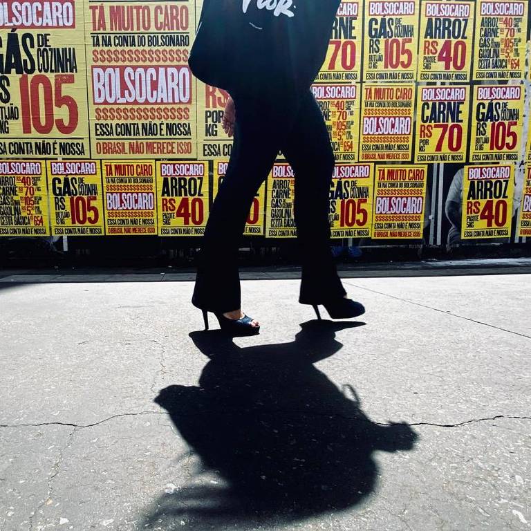 Uma mulher caminha em frente a cartazes da campanha 'Bolsocaro' na Avenida Paulista 