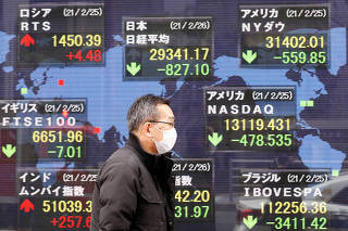 FILE PHOTO: A man walks past a stock quotation board at a brokerage in Tokyo, Japan