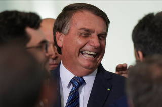 Brazil's President Jair Bolsonaro laughs near mayors after a ceremony to launch a program to help new mayors, at Planalto Palace in Brasilia