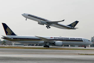 FILE PHOTO: FILE PHOTO: A Singapore Airlines Airbus A330 plane takes off behind a Boeing 787 Dreamliner at Changi Airport in Singapore