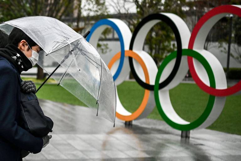 Homem passeia em frente aos anéis olímpicos do Museu Olímpico de Tóquio