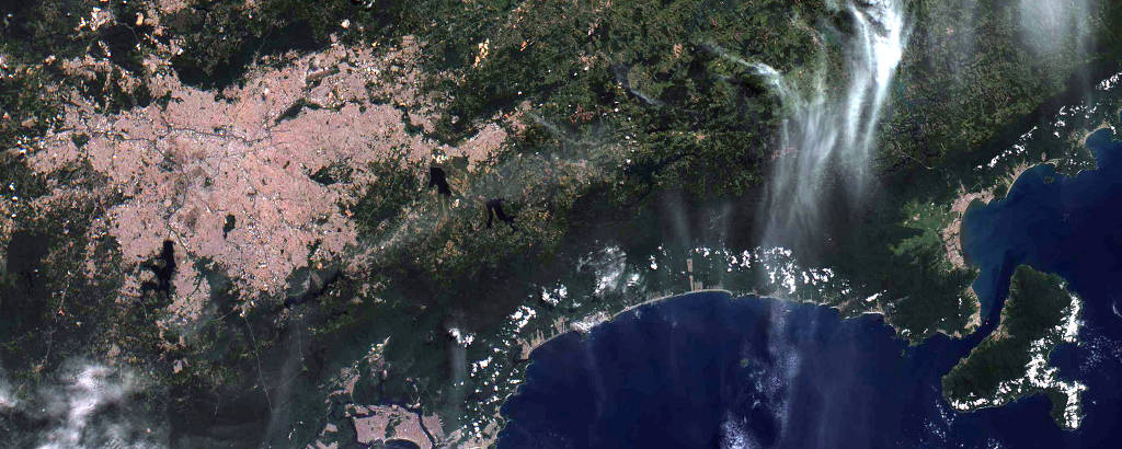 Imagem de satélite mostrando uma área verde, de mata, próxima a uma aglomerado urbano; no canto inferior direito também é possível ver o mar
