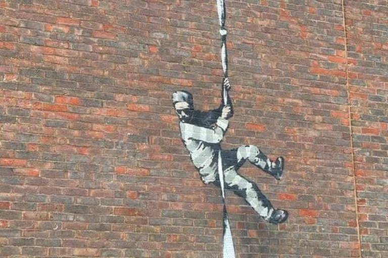 Grafite em parede de tijolos mostra homem descendo por uma corda