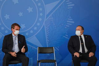Brazil's President Jair Bolsonaro gestures to Brazil's Health Minister Eduardo Pazuello during a ceremony in Brasilia