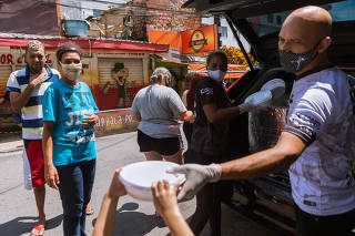 Voluntários distribuem marmitas para moradores, em Heliópolis (SP)
