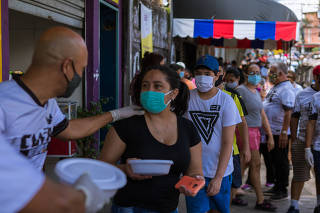 Voluntários distribuem marmitas para moradores, em Heliópolis (SP)