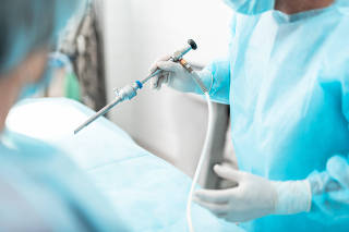 Surgeon in blue sterile gown using laparoscope during surgical operation