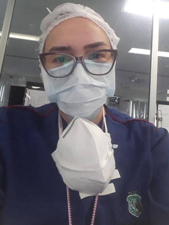 Fisioterapeuta de máscara, touca e avental hospitalar faz selfie
