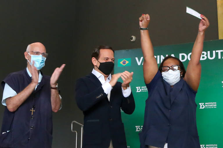 João Doria aplaude a aplicação da segunda dose da vacina na enfermeira Monica Calazans, primeira pessoa no Brasil a receber o imunizante contra a Covid.