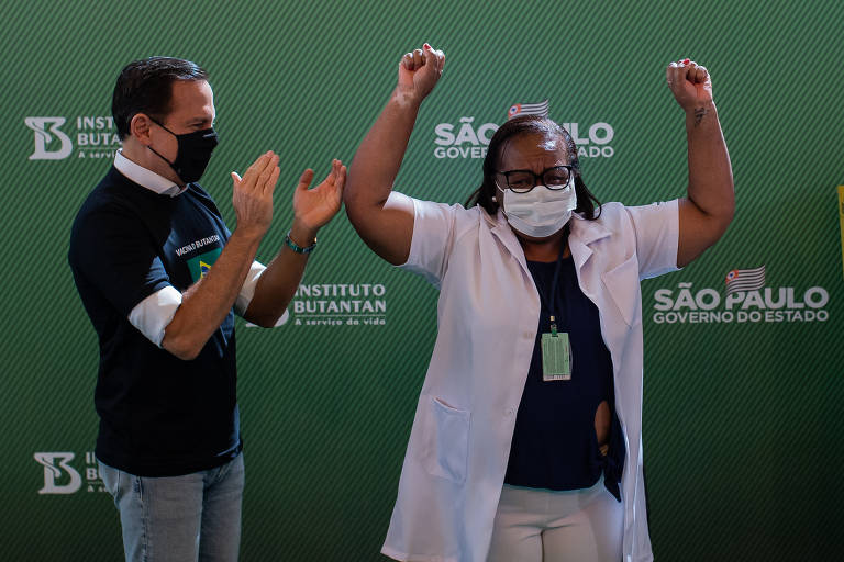 O governador de São Paulo, João Doria, aplaude a enfermeira do hospital Emílio Ribas Monica Calazans. Ela foi a primeira brasileira a ser vacinada contra a Covid-19 no país, em 17 de janeiro