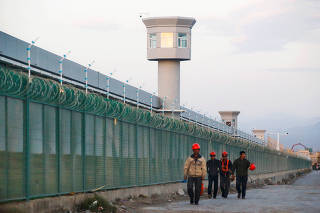 FILE PHOTO: Workers walk by the perimeter fence of what is officially known as a vocational skills education centre in Dabancheng