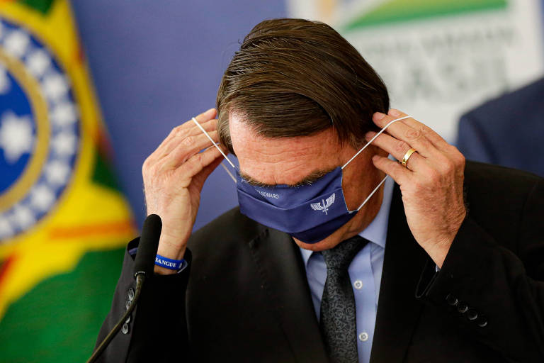 Bolsonaro tenta colocar uma máscara com brasão da FAB em evento no Palácio do Planalto