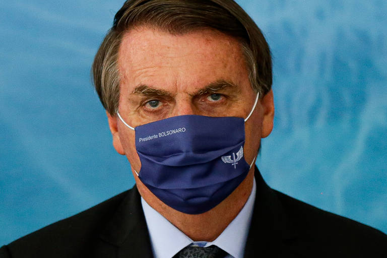 Presidente Jair Bolsonaro usa máscara com seu nome durante anúncio de investimentos para o programa Águas Brasileiras, no Palácio do Planalto, em 23 de março.