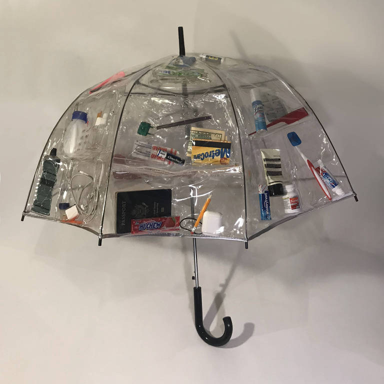 guarda-chuva feito de plastico transparente e com artigos para viagem inseridos dentro da lona