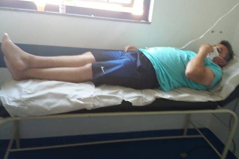 Valmírio Lopes Cardoso, 49, aguarda leito de UTI em maca coberta por papel no Hospital Cidade Tiradentes, em SP