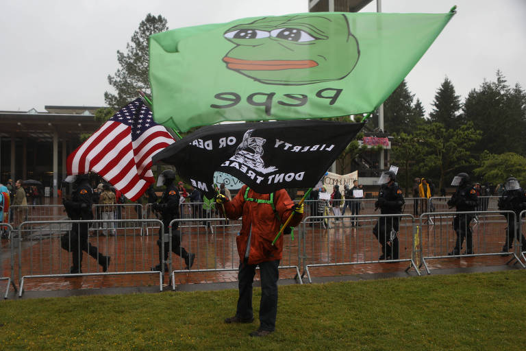 Um homem agita uma bandeira com Pepe, o sapo, um símbolo da alt-right, em uma manifestação 