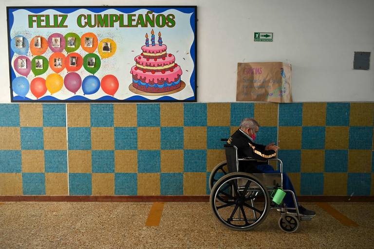 Homem idoso em cadeira de rodas perto de placa de feliz aniversário