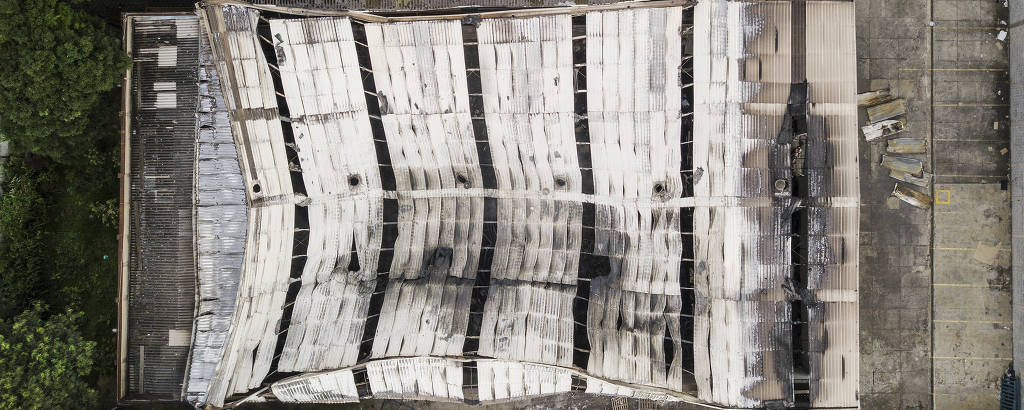 Imagem aérea mostra teto de alumínio de galpão queimado e cedendo