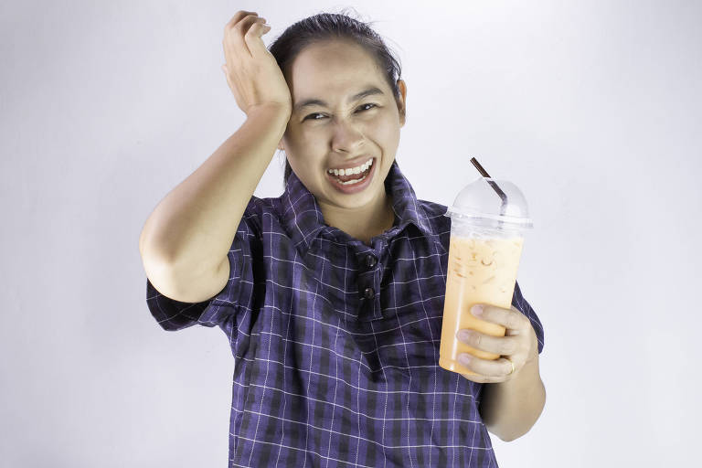 Asian young woman touching head with hand because she Brain freeze from drinking cold water. Health care concept.