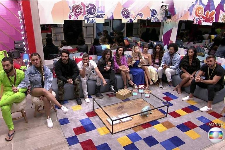 Imagem mostra os participantes do Big Brother Brasil 2021 sentados em uma sala