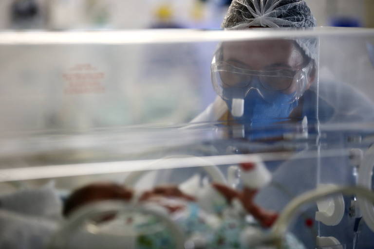 Enfermeira observa bebê em incubadora na UTI