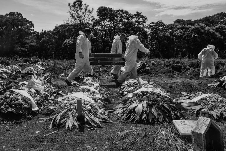 Sepultadores, carregando caixão, trabalham em covas abertas no cemitério de Vila Formosa, na capital paulista