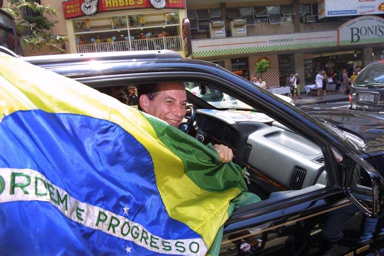O candidato do PPS à Presidência, Ciro Gomes, com uma bandeira do Brasil, ao entrar no carro depois de caminhada pela avenida Nossa Senhora de Copacabana (zona sul do RJ), na véspera do primeiro turno das eleições de 2002.
