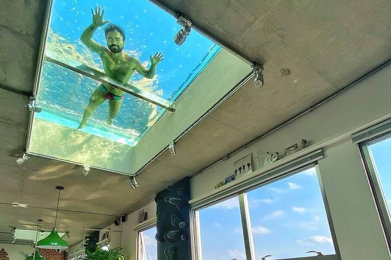 Homem aparece nadando em piscina transparente no teto da sala