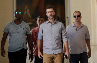 Rio de Janeiro assemblyman and congressman elect Marcelo Freixo walks with his security men after attending a news conference on the investigation of a plan to kill him according to investigative police in Rio de Janeiro