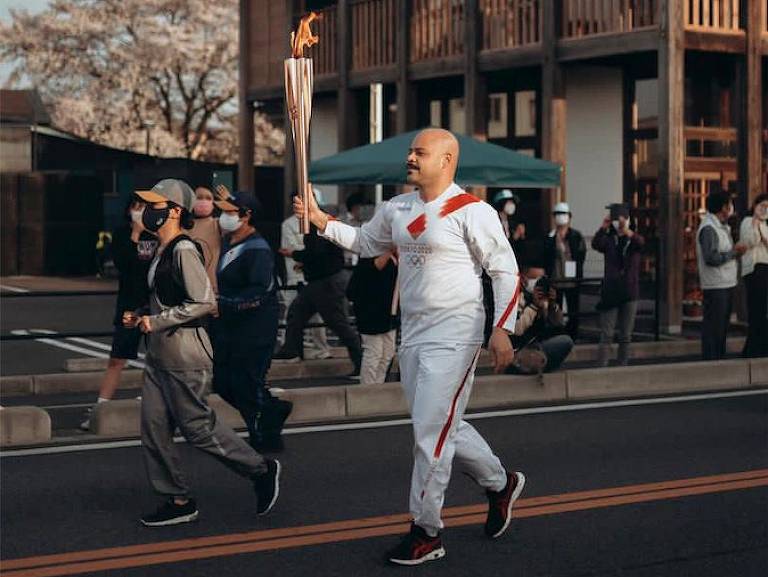 Homem trota pela rua segundo a tocha olímpica