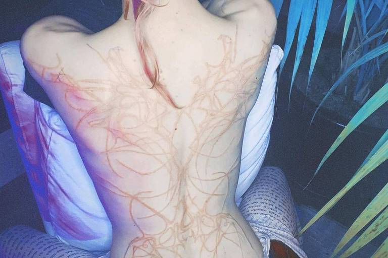 Tatuagem de marcas vermelhas nas costas da cantora Grimes