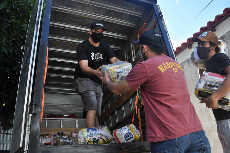 Três homens descarregam cestas de alimentos de um caminhão