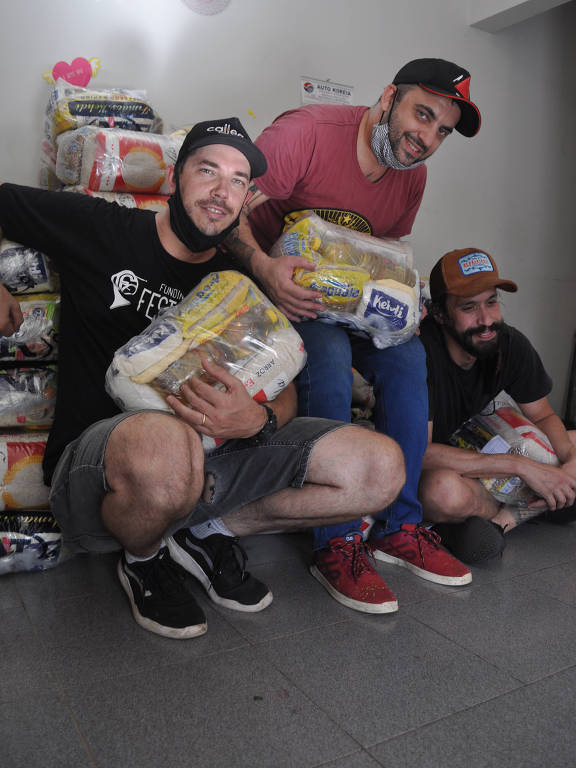 três homens de boné com alimentos doados atrás deles