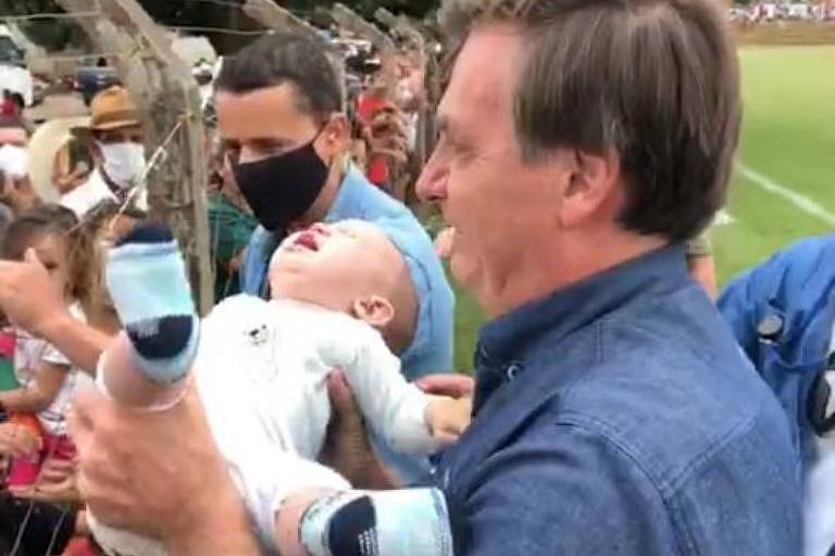 O presidente Jair Bolsonaro segua um bebê, que chora, ao cumprimentar apoiadores em Goianápolis