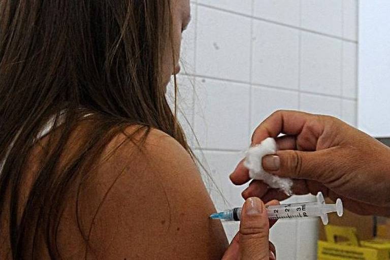 mulher jovem é vacinada 