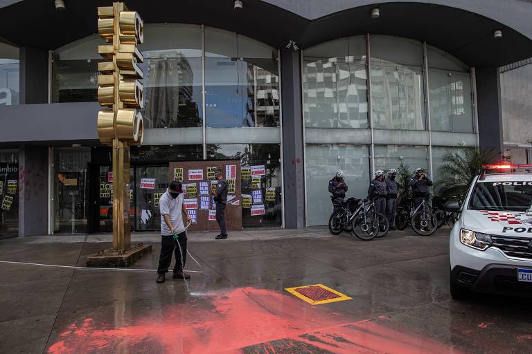 Funcionários limpam calçada e fachada do Banco Safra na avenida Faria Lima, em São Paulo