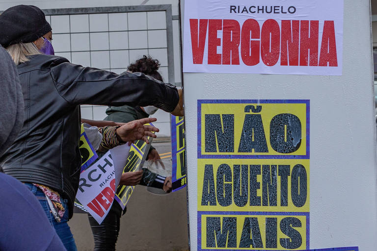 Manifestantes da Frente Povo Sem Medo fixam cartazes na sede da Riachuelo, zona norte de São Paulo