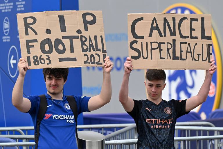 Dois jovens com camisetas dos times e cartazes escritos "RIP futebol" e "cancele a Superliga"