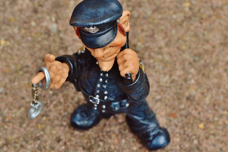Figura de brinquedo representando policial, uniformizado, segurando algema e cassetete