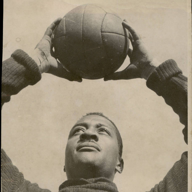 Barbosa, goleiro titular da seleção brasileira na Copa de 1950, segura a bola com as duas mãos, acima da cabeça, em treino no Rio de Janeiro