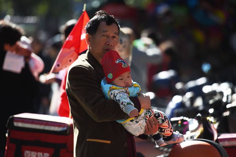 Homem segura bebê próximo a hospital em Pequim