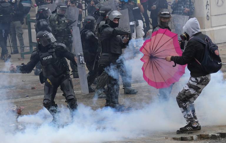 Manifestante usa guarda-chuva para se proteger de gás lacrimogêneo lançado por policiais durante confronto em protesto contra projeto de reforma tributária do presidente da Colômbia, Iván Duque, em Bogotá